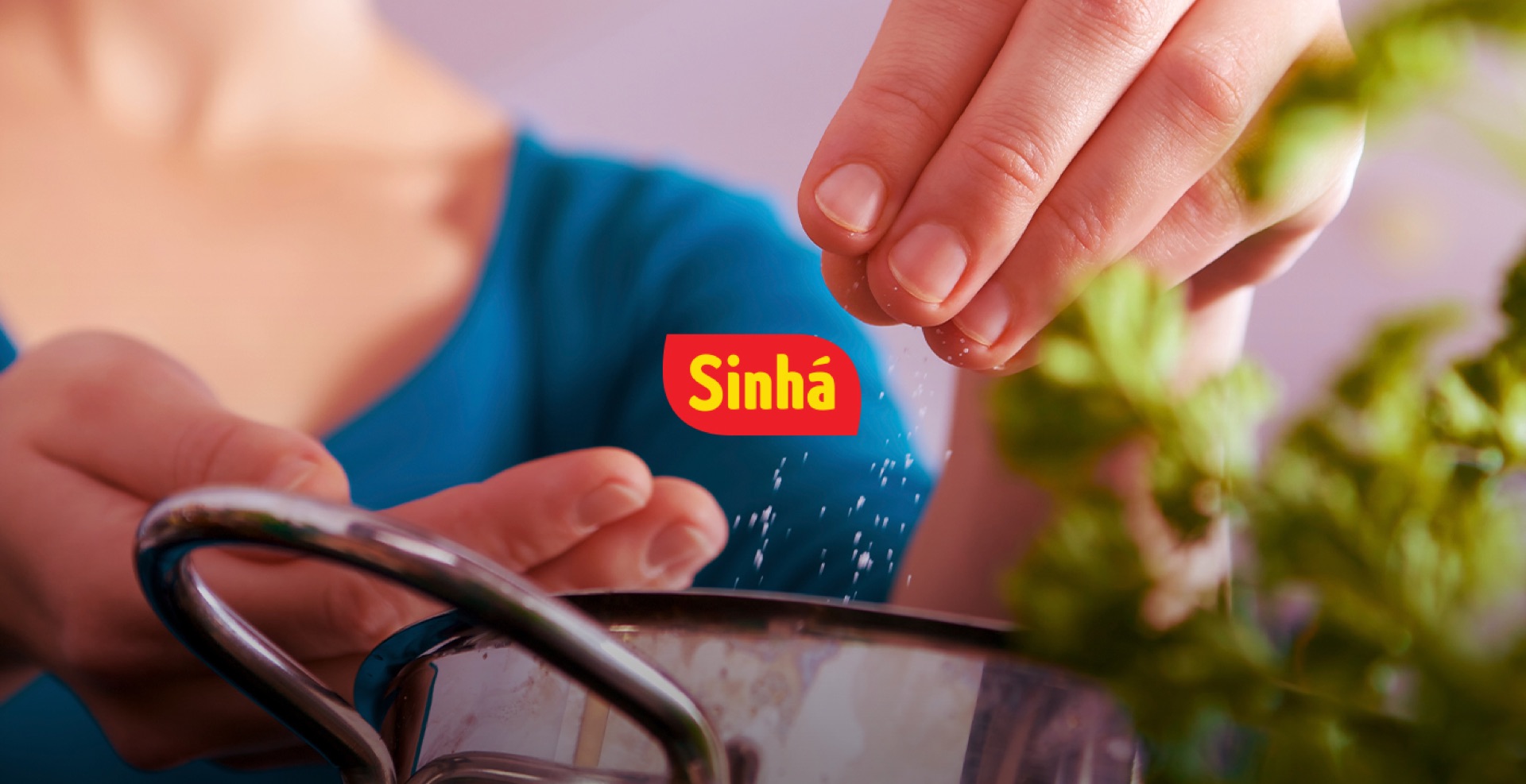 Sinhá: mão temperando uma panela, com o logotipo da marca